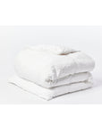 The Coyuchi Inc Org Relaxed Linen Duvet in Alpine White (Queen), crafted from organic linen and colored with low-impact dyes, is neatly folded on a white surface against a plain white background.