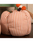 The Faire Pumpkin is a soft fabric ornament with orange and white stripes, a decorative stem featuring orange pom-poms and beige tassels—perfect for cozy farmhouse decor.