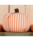 The Faire Pumpkin is a decorative fabric piece with orange and white vertical stripes and a dark brown stem, ideal for farmhouse decor and displayed against a light wooden background.