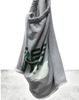 The FreeCity Cutoffs by Free City (sparrow, LLC) is a light gray blanket in lightweight French terry with a white dove and partial green text, draped elegantly against a light background.