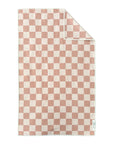 The Faire Double Sided Hand Towel features a pink and white checkerboard waffle weave, neatly folded at one corner. A small white tag is sewn into the bottom right edge.