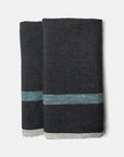 The CH Tea Towels S/2 by Faire feature dark gray linen with a horizontal teal stripe and thin light gray edge, shown folded side by side on a white background.