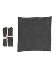 Two Stonewashed Linen Napkins from Creative Co-op's S/4 set—one folded and tied with white cotton tape, the other unfolded—are displayed side by side on a white background in a charcoal color.