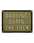 The Oxford Pennant "Darling Damn The Luck" Camp Flag (18x24) features green fabric, black trim, gold grommets, and bold black-outlined lettering—a nod to Cleveland Country Blues style.
