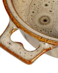 Close-up of the Creative Co-op Brie Baker with Bamboo Spreader, a stoneware dish featuring a speckled beige and brown glaze, textured surface, and a sturdy handle with a curved cutout.