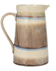 The Creative Co-op Pitcher w/ Stripes features a curved handle, glazed earthy brown, beige, and blue tones, plus a small pouring spout—perfect rustic serveware for any table.