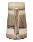 The Creative Co-op Pitcher w/ Stripes is a tall, cylindrical stoneware pitcher with a handle, featuring beige and brown glaze with blue and cream bands. Its glossy finish gives rustic charm to your serveware collection.