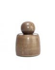 The Faire Olive Brown Stash Jar is a small, hand-thrown stoneware jar with a rounded base and spherical lid, finished in a subtle satin glaze and shown against a plain white background.