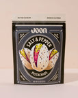 A black and beige resealable pouch of Faire Joon Pistachios stands upright. The front shows pistachio illustrations and highlights this healthy snack as high protein, non-GMO, and with no added sugar.