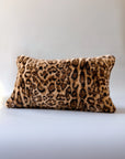 Leopard print lumbar pillow with plush faux fur cover by Faire, shown on a sleek white surface.