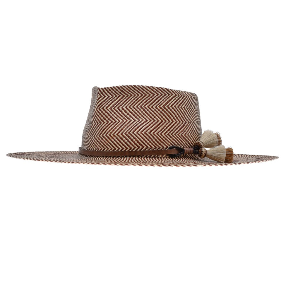 A stylish Emery XLong Brim hat from Ninakuru with a chevron pattern and adorned with decorative horsehair tassels on the side. The hat features a wide brim and a distinctively shaped crown.