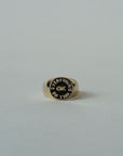 The Faire Everything Will Be OK Ring is a gold-plated signet with “EVERYTHING IS OK” engraved on its round face, shown on a plain light grey background.