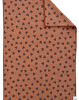The Faire Double Sided Hand Towel features a brown rectangular design with small black hearts scattered across both sides; one corner is folded to show the reversible pattern.