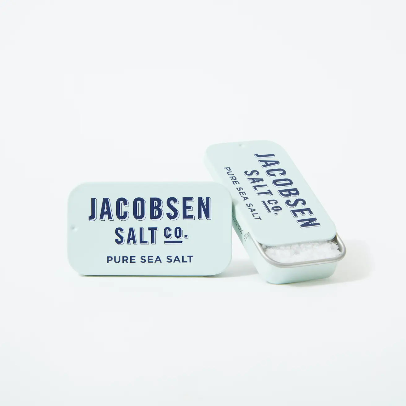Two small Kosher Sea Salt slide Tins from Faire are shown on a white background—one open to display the salt inside. The tins are light blue with dark blue text, creating a clean, modern look.