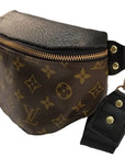 The Faire Upcycled Belt Bag features brown canvas with a monogram pattern, gold zipper, black adjustable strap with gold hardware and snap buttons.