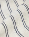 Close-up of the Kemptown Stripe Linen Euro Sham by Faire, featuring off-white European linen with thin, diagonal navy blue stripes. The breathable fabric looks soft, slightly textured, and gently folded.