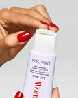 A hand with red nails opens a white 1.7 fl oz (50 ml) Faire "Let's Neck - Neck Serum w/ Cooling Applicator" bottle, showing its roller tip for neck and décolleté. The background is plain gray.