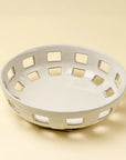 The Indaba Cypress Fruit Bowl L is a round, white ceramic bowl with square cutout patterns—an elegant kitchen accessory shown on a light beige background.