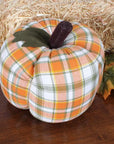 The Faire Pumpkin features an orange, white, and green plaid fabric with a felt leaf, dark brown stem, and autumn leaves—making it the perfect farmhouse decor accent for fall.