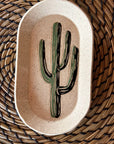 The Faire Saguaro Oval Trinket Dish features a hand-painted green cactus at its center, offering desert-inspired charm—ideal for organizing jewelry or keys and adding a stylish accent to your space.