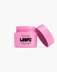An open pink jar of Faire’s LOOPS Glow Lip Mask sits against a white background—ideal for nourishing your lips.
