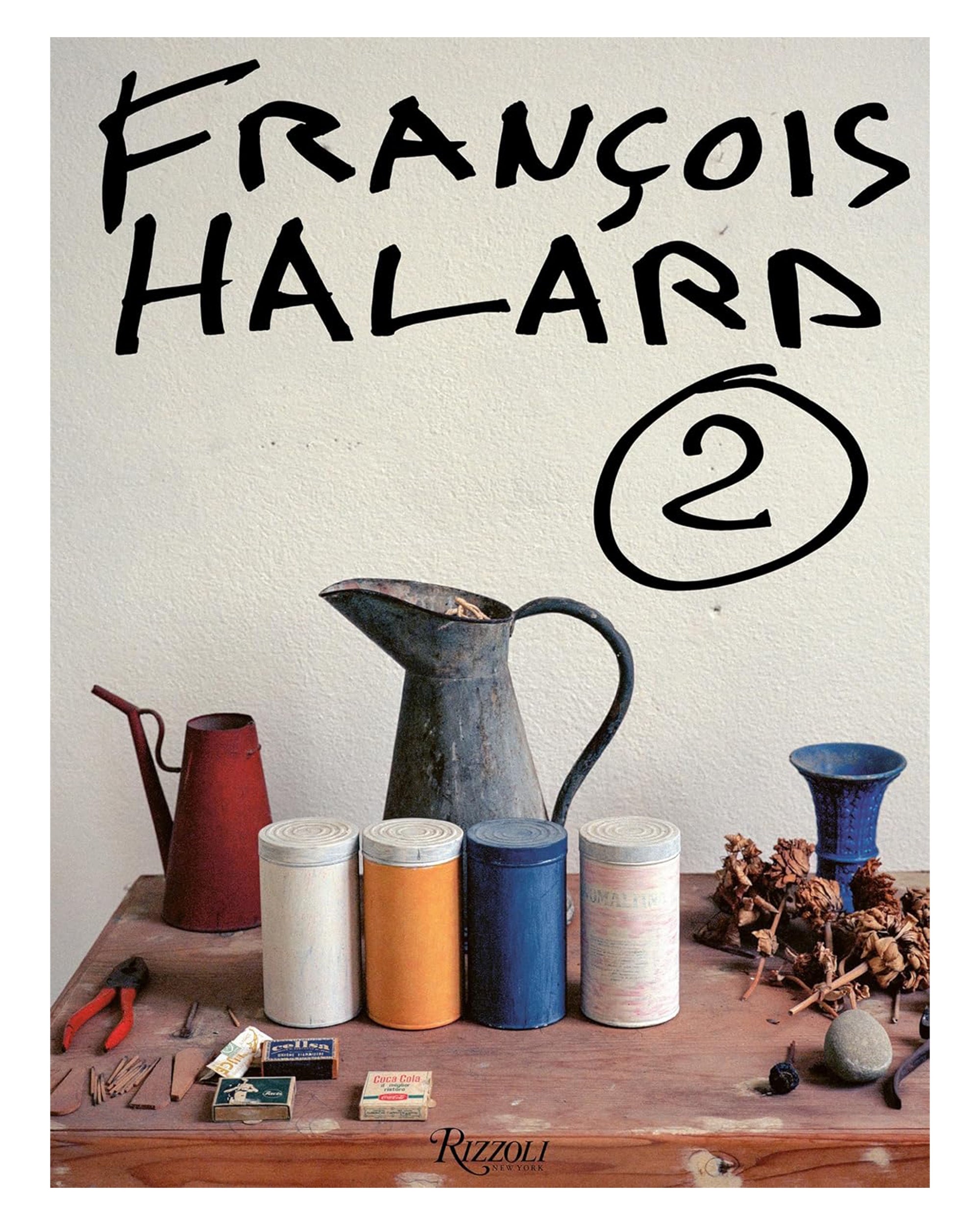 A wooden table with art supplies, cans, a pitcher, and pine cones sits by a white wall under large text reading "Francoise Halard." Published by Random House, it showcases photographer Francoise Halard’s impact on design history.