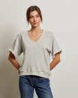 A woman wearing a Perfectwhitetee French Terry SS Crew in light gray and blue jeans stands against a plain, light-colored background with her hands behind her back.