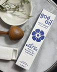 A box of Goe Oil by Jao Limited sits on a round marble tray with a wooden massager, white dish, and glass dropper—ideal for moisturizing skin and enhancing hair rejuvenation.