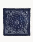 The Hachiko Scarf by KUJTEN is a navy blue square bandana made from soft printed cashmere with a white paisley and floral design, intricate borders, and fringed edges.