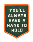 The Oxford Pennant “You'll Always Have a Hand to Hold” camp flag features forest green fabric, orange trim, and bold white block lettering.