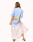 Mia Happimess Studio Shirt by Kerri Rosenthal in a lively pattern, styled with a light pink skirt, shown from the back.