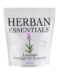 A white package of Essential Oil Towelettes is shown. The packaging prominently features the brand name Herban Essentials, a lavender flower illustration, and indicates that it contains 20 aromatherapeutic towelettes infused with calming lavender essential oil.