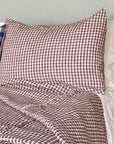 The Hertford King Duvet by Modernplum features brown, white, and navy plaid linen bedding with a pillow and blanket, styled against a neutral wall.
