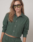 Olive-green sunglasses paired with THE SHIRT’s white-stitched Harper shirt and matching pants, modern casual style.