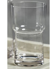 The Zodax Blown Glass HB is a clear, empty highball glass with a unique hourglass shape and thick base, measuring 3.25 x 5.75 inches, displayed on a light-colored surface.
