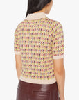 A person with long dark hair, seen from the back, wears Mother's Hot Under the Collar Polo—a short-sleeved knit top with a checkerboard pattern, beige collar and cuffs—paired with high-waisted burgundy pants.