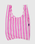 The Baggu Standard by Baggu is a rectangular, reusable bag made from recycled ripstop nylon with vertical pink and white stripes. It has wide handles, is machine washable, and is shown laying flat against a white background.