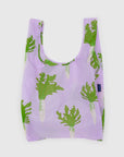 The Baggu Standard by Baggu is a reusable bag made from recycled ripstop nylon, with a light purple background and green daikon radish print. It features wide handles, a soft rectangular shape, and is machine washable for easy care.