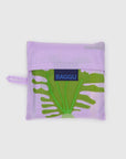 The Baggu Standard by Baggu is a folded reusable bag in a lavender pouch, made from recycled ripstop nylon with a green botanical print partly visible and a blue BAGGU label on the front. It's machine washable for easy care.