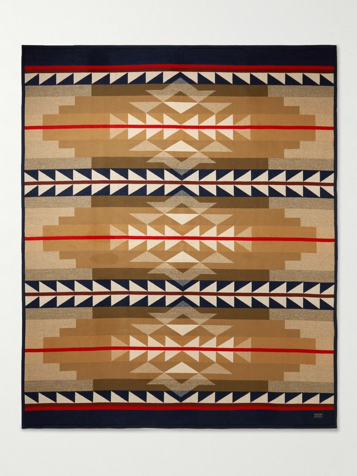 The Pendleton/Babbitt's Wholesale Jacquard Robe is a USA-made wool blanket with a geometric, Native American-inspired pattern in tan, brown, navy, red, and cream, featuring symmetrical triangles and diamonds.