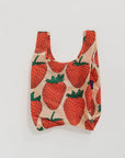 The Baby Baggu by Baggu is a reusable shopping bag made from recycled ripstop nylon, featuring a beige background with red strawberries and green leaves. Machine washable, it combines practical use with a playful design.