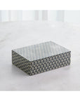 The 9.94040 Interwoven Box MD by Global Views is a rectangular decorative box featuring a black, white, and gray geometric star pattern, shown on a light surface with sheer white curtains in the background.