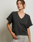 A woman wearing the Perfectwhitetee French Terry SS Crew and light gray sweatpants stands against a neutral background, looking relaxed. The cozy French terry material adds comfort to her laid-back style.