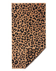 The Typical Wild Leopard Bath Towel features a bold black leopard print on a tan background, with one corner folded to show the underside.
