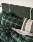 Jack Check Sham from Libeco Home on a bed with a green striped headboard for a fresh, classic bedroom look.