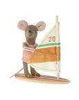 The Maileg Little Sister Beach Surfer by Maileg is a plush mouse toy dressed in a ruffled one-piece, standing on a striped wooden surfboard with an orange and green sail featuring the number "20"—perfect for imaginative play.