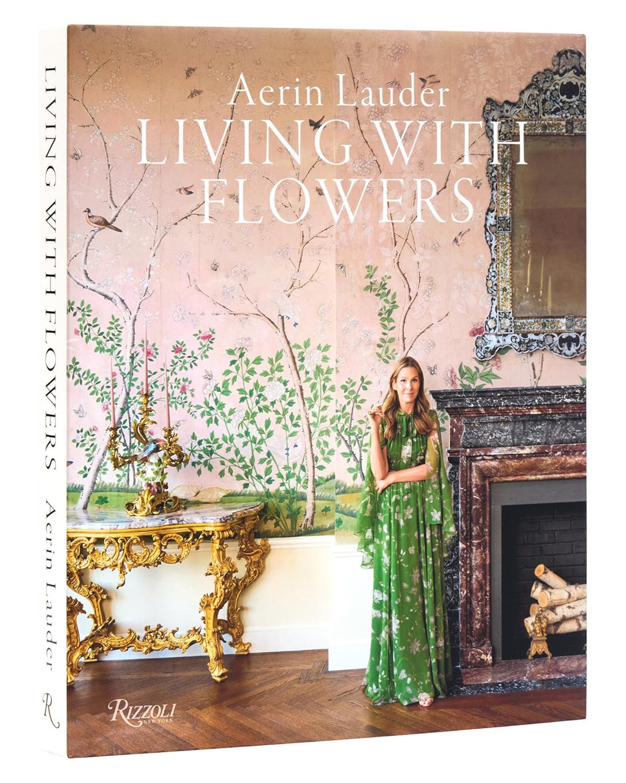 The book "Aerin Lauder Living With Flowers" by Random House features a woman in a green floral dress by a fireplace with pink floral wallpaper—an elegant addition for entertaining or enhancing your home décor.