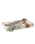 The Loma Matelasse OS Throw by Coyuchi Inc is an oversized plaid throw in brown, beige, white, and light green. Made from organic cotton with a checkered pattern and fringed edges.