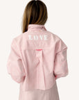 Pink jacket layered over a Kerri Rosenthal Tia Love Stripe Shirt, seen from behind in a casual, modern setting.