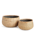 The Wovenshire Low Bowl L by Napa Home & Garden is a large, round woven rattan basket lined with black plastic. Its natural bamboo color and rustic design make it versatile for storage or décor in any space.